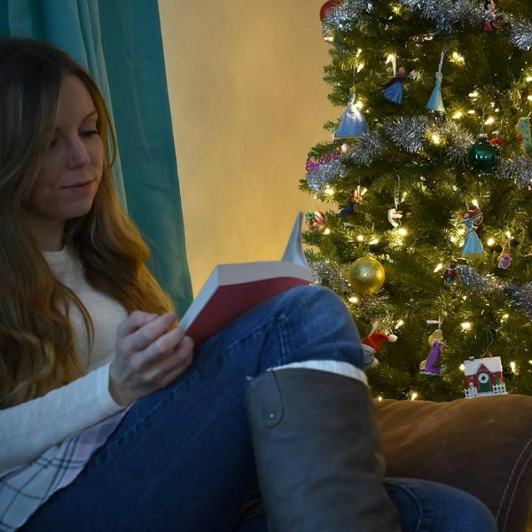 reading Bible by Christmas tree